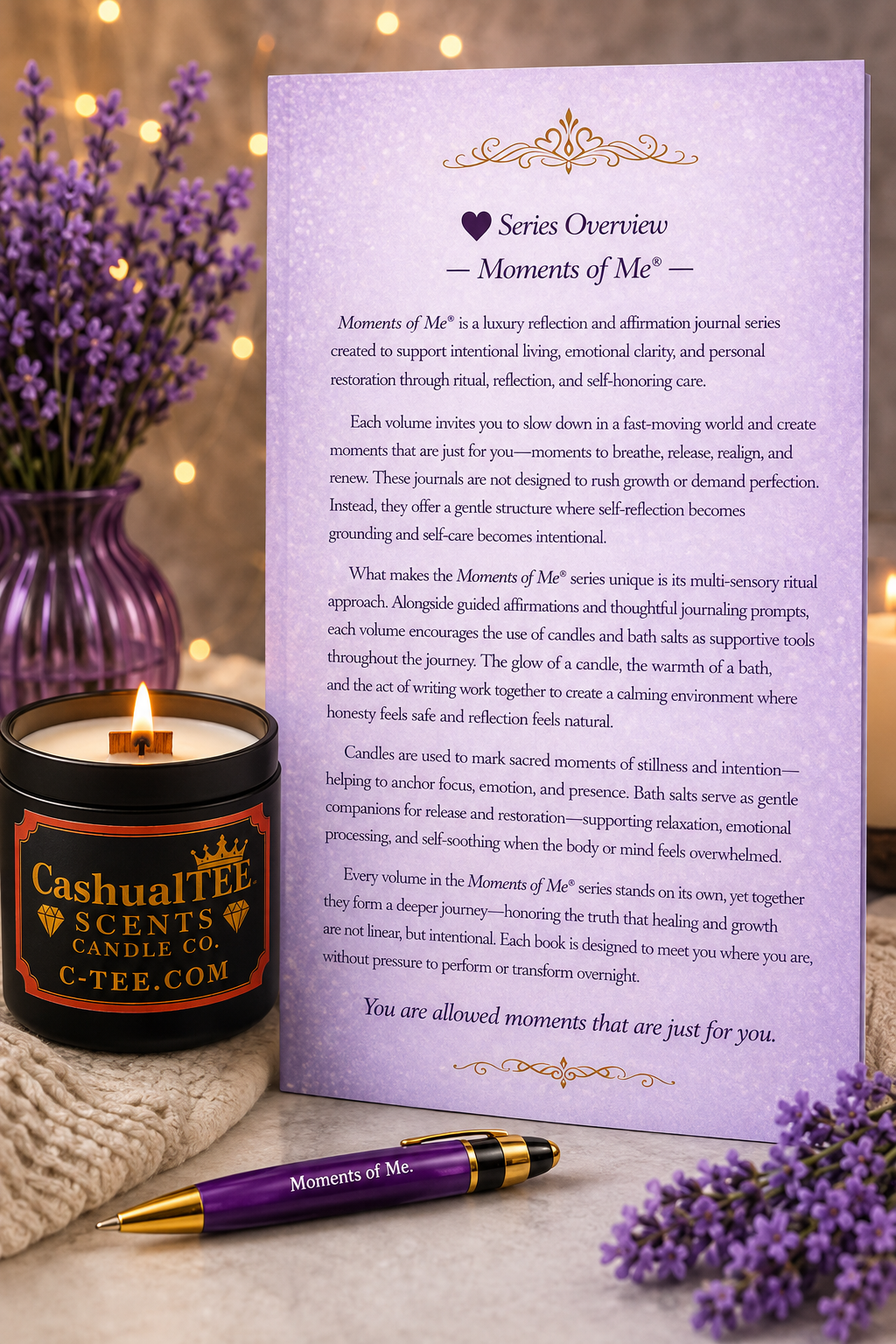 A printed journaling prompt card titled 'Moments of Me' with a purple heart icon and decorative header, displayed on a table with a purple pen, a lit candle in a black jar labeled 'Cashualltee Scents Candle Co.', and lavender flowers in the background.